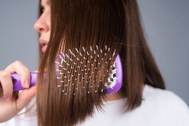 Saçlarını tarayan kadını kapat. Uzun saç fırçası olan güzel kız..