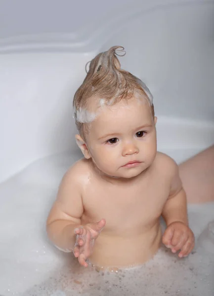 Todler in shower. Little boy in bathtub with fluffy soap bubble. Baby bathes in a bath with foam and soap bubbles. — Stock Photo, Image