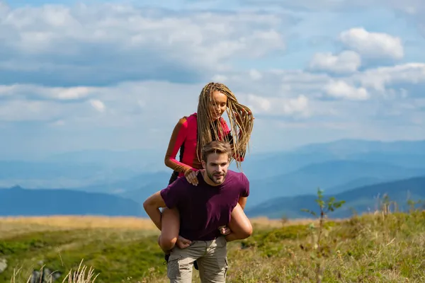Vriendje die een vrouw meelift op Traver. Man draagt vrouw terug in een zomerse natuur. — Stockfoto