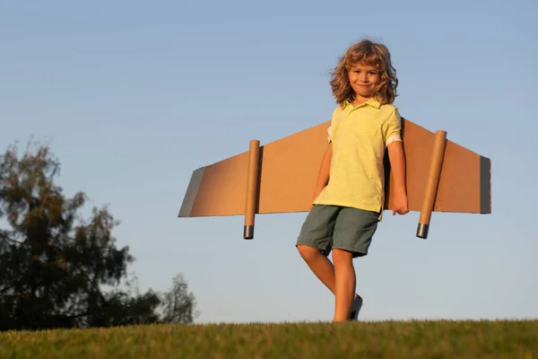 おもちゃの飛行機の翼で遊んでいる子供の男の子。パイロットになる夢。スーパーヒーロー飛行。青い空の上の子供との休暇旅行. — ストック写真