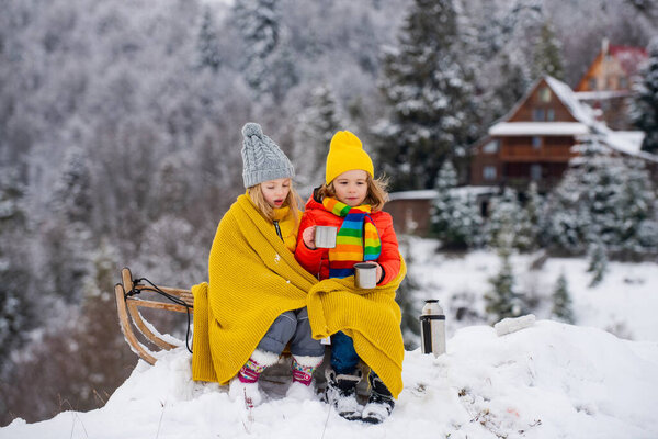 Kids boy and little girl enjoying a sleigh ride. Children sibling together sledding, play outdoors in snow on mountains in winter. Kids brother and sister on Christmas vacation.