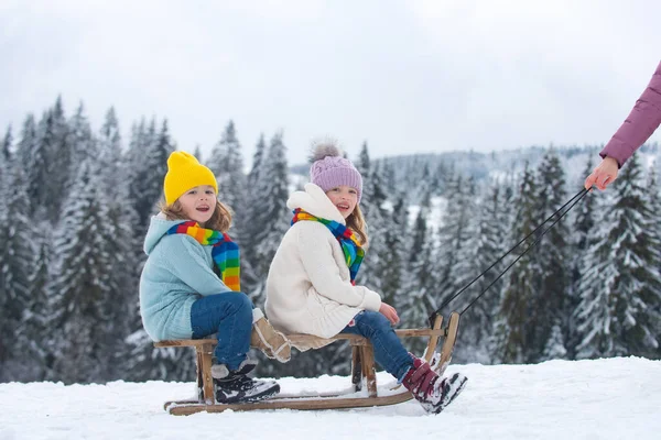 Kids boy and little girl enjoying a sleigh ride. Children sibling together sledding outdoors in snow on mountains in winter. Kids brother and sister on Christmas vacation. Family christmas holiday. — Stock Photo, Image