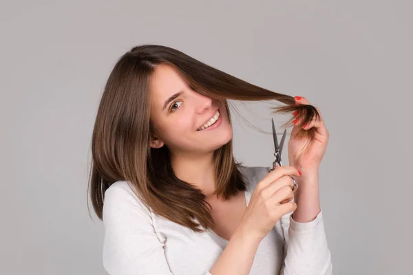 Szczęśliwa kobieta z nożyczkami obcinającymi włosy. Piękna dziewczyna z prostymi włosami z profesjonalnym nożyczkiem. Koncepcja pielęgnacji włosów. — Zdjęcie stockowe