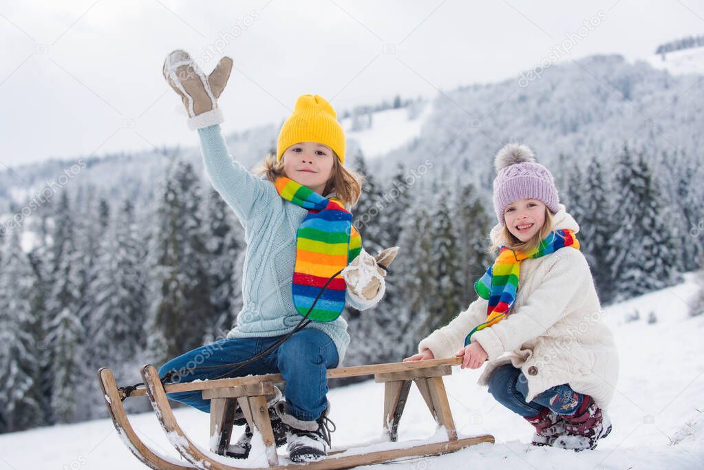 Children enjoying winter, playing with sleigh ride in the winter forest. Kids play with snow. Winter vacation concept. Kids playing in the winter forest.