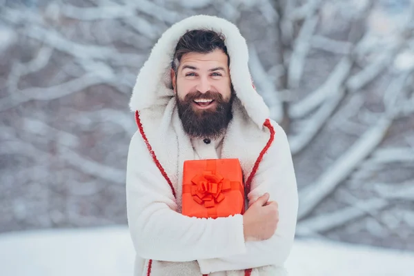 Uomo in abito natalizio con regalo vicino alla neve. Babbo Natale uomo a Natale. — Foto Stock