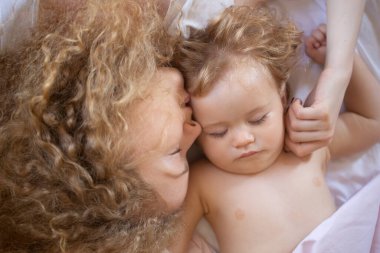 Anne ve bebek yatakta uyuyor. Yatak odasında aile sabahı. Günaydın..