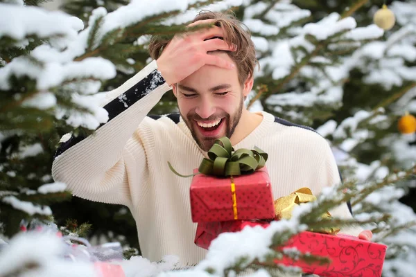 Człowiek śmiejący się z czerwonych pudełek w śniegu. Koncepcja świąt. Macho z prezentami w zimowy dzień. Pozdrowienia sezonowe i prezenty świąteczne — Zdjęcie stockowe