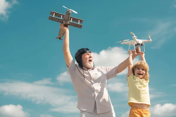 空に対しておもちゃの飛行機とクワッドコプターの無人機で遊んで孫の子供と祖父。飛行機旅行の夢を持つ子供のパイロット航空機。家族関係祖父と子. — ストック写真