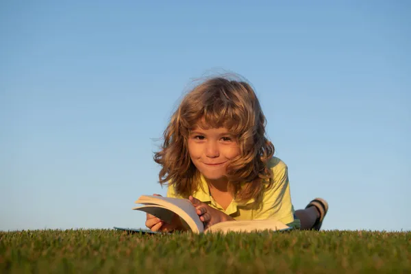 Детское воображение, мечтательные дети. Милый ребенок читает книгу о зеленой траве. — стоковое фото