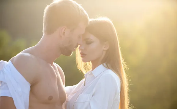 A fiatal szerelmesek együtt töltik az időt naplementekor. A férfi ölelkezik és megcsókolja az érzéki nőt.. — Stock Fotó