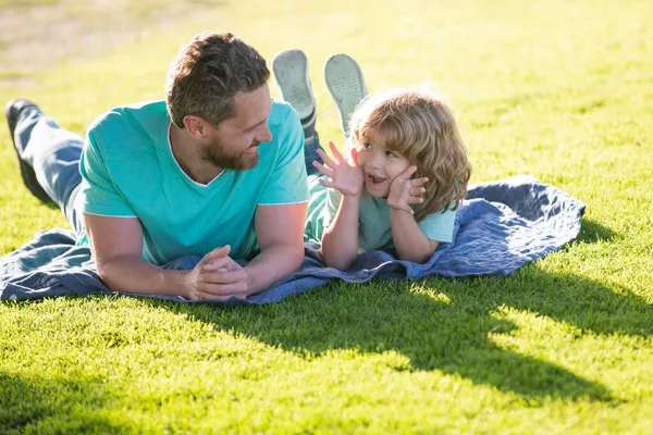 Feliz pai e filho desfrutando de tempo de verão deitado na grama, férias em um parque ensolarado. — Fotografia de Stock