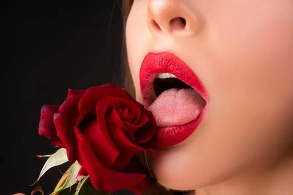 립스틱 클로즈업 한 입술. 장미와 아름다운 입술을 가진 아름다운 여인. 붉은 장미를 가진 여성, 매크로, 검은 배경에. — 스톡 사진