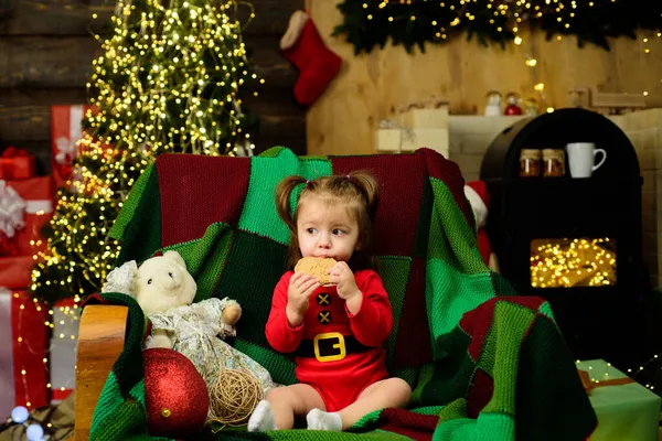 Nettes Babygesicht mit Weihnachtsmütze in der Nähe des Weihnachtsbaums. Glückliche Kindheit. Neujahrskinder. — Stockfoto