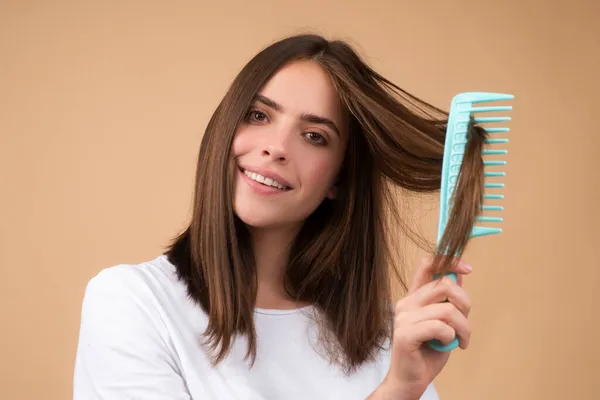 Young woman combing healthy and shiny hair, isolated on studio. — Stock Photo, Image