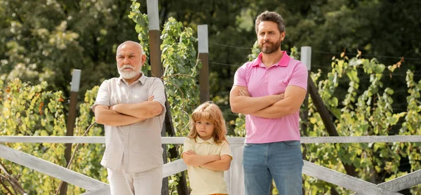 Banner of male generation family together with three different generations ages grandfather father and son in summer garden.