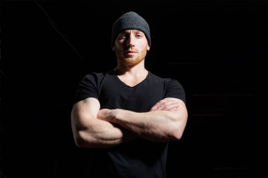 Kollarını kavuşturmuş genç ve seksi bir adamın portresi. Siyah stüdyoda erkek model..