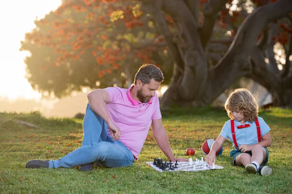 Šachová škola pro děti. Šťastná rodina venku. Otec a syn hrají šachy na jarní zahradě. — Stock fotografie