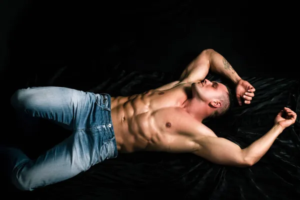 Wellness, wellbeing concept. Shirtless muscular bodybuilder man reading book, laying on bed. Luxury lifestyle. — Stock Photo, Image