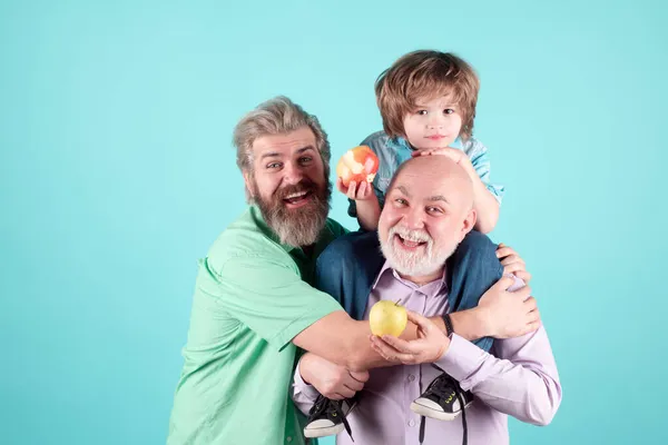 Farfar far och på kramar och äter äpple. Män i olika åldrar med ömhet kram, barn kärlek, tillgiven. — Stockfoto