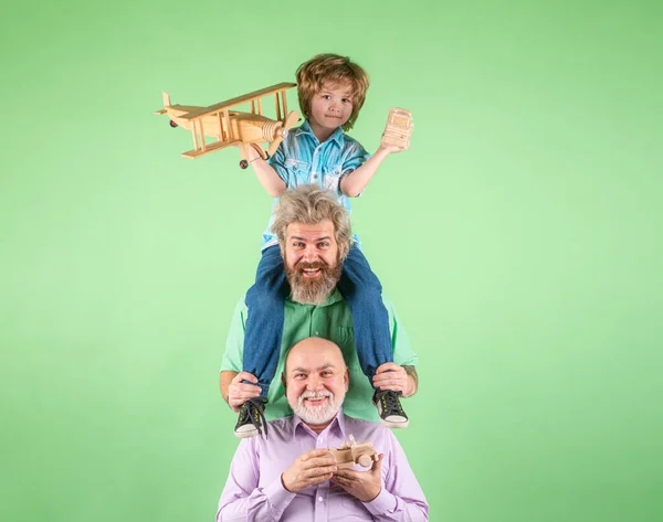 Niño hijo con padre y abuelo con un avión de juguete juega en el fondo aislado. Aventura familiar, imaginación, innovación e inspiración. Hombres en diferentes edades. — Foto de Stock