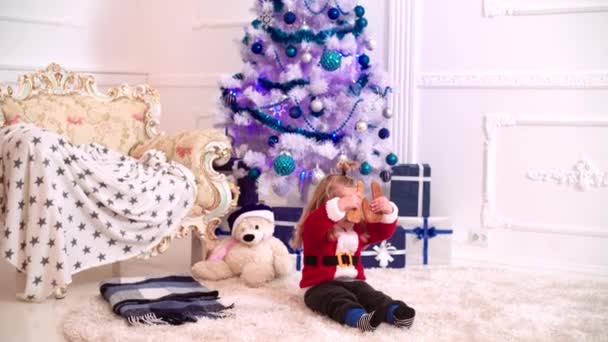 Bebê bonito em uma camisola de inverno vermelho e chapéu de Papai Noel segurar biscoitos de Natal na árvore de Natal. Feliz Natal e Feliz Ano Novo para a criança. — Vídeo de Stock