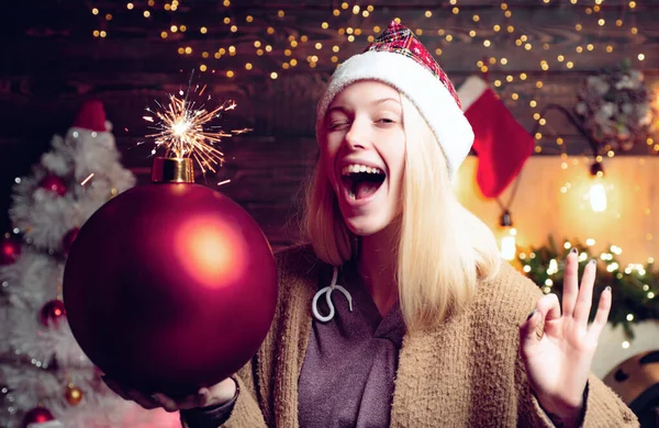 Vánoční žena drží bombu. Šílené veselé Vánoce a šťastný nový rok. Šílená komická tvář. Mladá vtipná žena mrkne. Comic grimace. — Stock fotografie