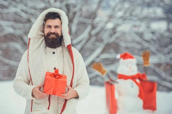 Handsome Winter Man with gift and snowman in frosty winter Park outdoor. — Stock Photo, Image