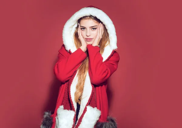 Mujer de Navidad con sombrero rojo. Chica feliz celebrar el año nuevo sobre fondo rojo. Fiesta de Navidad y vacaciones de invierno. Mujer en traje de santa con cara bonita —  Fotos de Stock