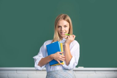 Sınıfta okuyan genç bir üniversite öğrencisinin portresi. Tahta altyapısı var. Kalem ve kitapla gülümseyen yaratıcı genç bayan öğrenci..