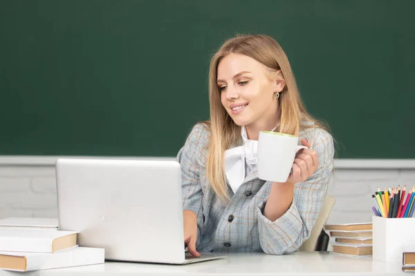 Studente universitaria che beve caffè o tè, lavora su un computer portatile in classe, si prepara per un esame. — Foto Stock