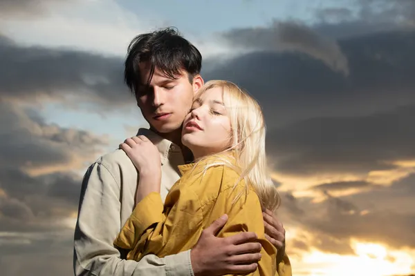 Retrato de casal encantador apaixonado no pôr do sol. Jovem namorada sensual feliz ao beijo apaixonado de seu namorado. Bonito jovem abraça sua mulher e beijos. — Fotografia de Stock