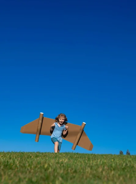 子供の男の子の想像力、小さなパイロットの夢とジェットパックの翼で飛ぶ。おもちゃのジェットパックで遊ぶ幸せな子供。緑の芝生の屋外で楽しんでいる子供のパイロット。成功、子供の革新とリーダーの概念. — ストック写真