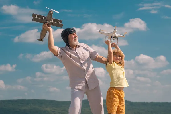 Niño y abuelo con avión y dron quadcopter sobre el cielo azul y las nubes de fondo. — Foto de Stock