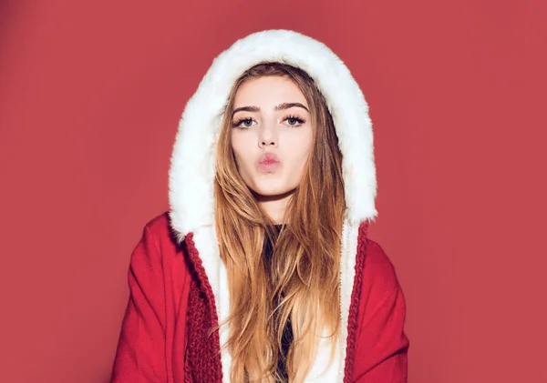 Χριστουγεννιάτικο φιλί. Ευτυχισμένο κορίτσι γιορτάζουν το νέο έτος στο κόκκινο φόντο. Χριστουγεννιάτικη γυναίκα με κόκκινο καπέλο. Γυναίκα με κοστούμι Άγιος Βασίλης με όμορφο πρόσωπο — Φωτογραφία Αρχείου