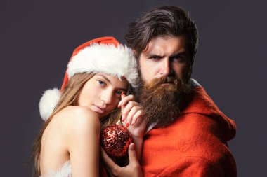 Noel Baba ve güzel genç kadın, gri arka planda Noel kostümü ve şapka giyiyorlar. Seksi noel çifti, birbirine aşık, kopyalama alanı