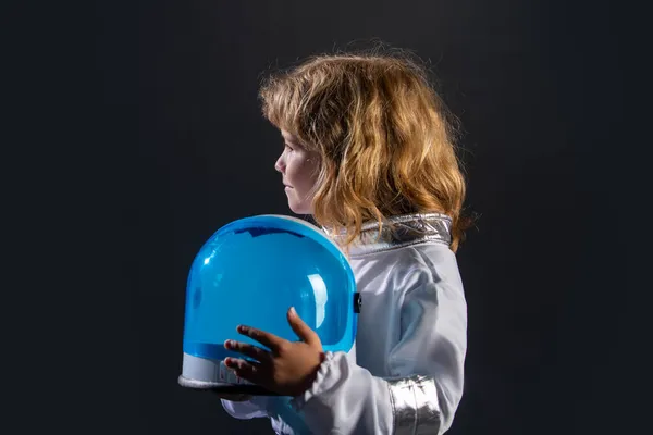 Ritratto di bambino divertente con casco da astronauta. Carino bambino astronauta ragazzo in tuta spaziale che tiene il casco su sfondo nero. — Foto Stock