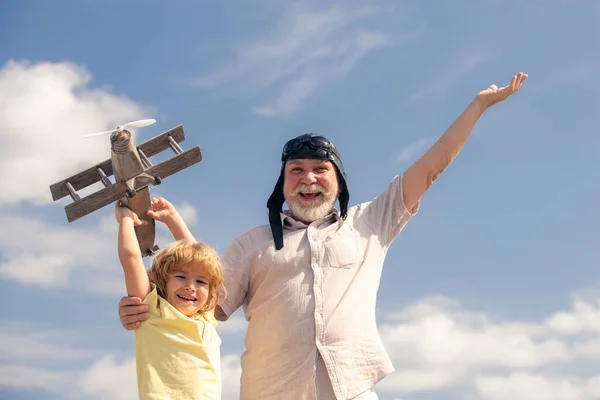 손자와 할아버지가 장난감 제트 팩 비행기와 하늘을 배경으로 하고 있다. 비행기 여행을 꿈꾸는 어린이 비행사. — 스톡 사진