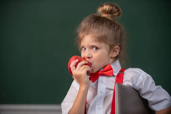 Μαθήτρια μαθήτρια στην τάξη, τρώει μήλο στο σχολείο. Αστεία παιδιά αντιμετωπίζουν από κοντά. — Φωτογραφία Αρχείου
