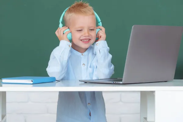 Chlapec ve sluchátkách pomocí notebooku a studovat online s učitelem videohovorů ve škole. Školení počítače. — Stock fotografie