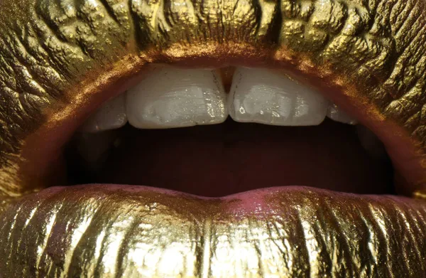 Macro close up of sexy golden lips, gold mouth. Glowing gold skin make-up. Glitter metallic shine golden lipgloss makeup.