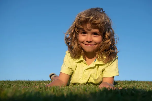 Dulce y feliz niño jugando en un césped en un parque en un manantial. Riendo, disfrutando de fresco. — Foto de Stock