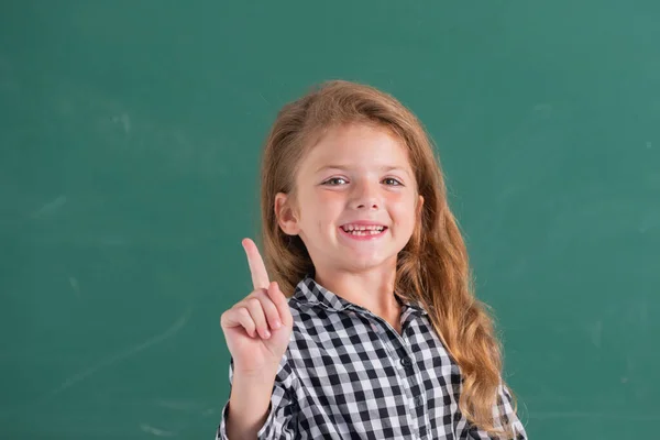 Retrato de alumna nerd escolar con expresión sorprendente apuntando con el dedo contra pizarra. —  Fotos de Stock