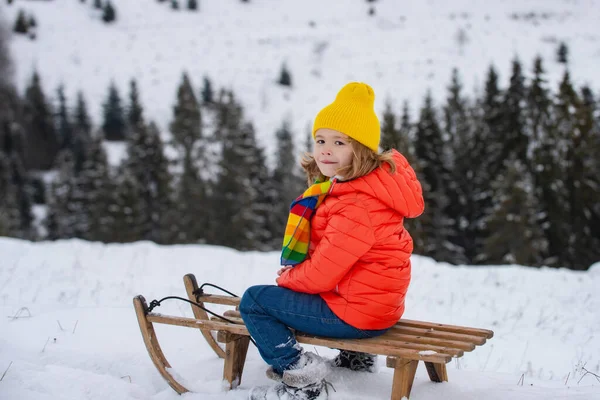 Boy kid enjoying a sleigh ride. Child on sleigh. Child plays outside in the snow. Winter, holiday and Christmas time. — Stock Photo, Image