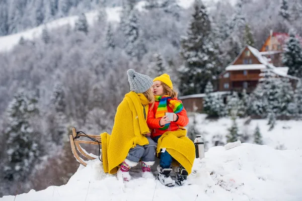 幸せな男の子と女の子は冬に眠っていた。冬には雪のスライドに乗っている子供たち。息子と娘はそりに乗るのを楽しむ. — ストック写真