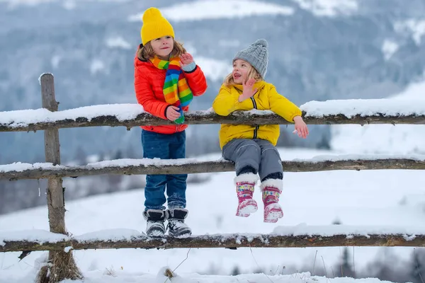 Duas crianças pequenas se divertir na bela natureza de inverno com neve coberta montanha rural. Roupas de malha de inverno para crianças. — Fotografia de Stock