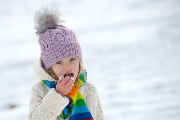 Zabawna dziewczynka jedząca śnieg w zimowy dzień. Podekscytowane święta Bożego Narodzenia. Przeziębienie dzieci i koncepcja grypy. — Zdjęcie stockowe