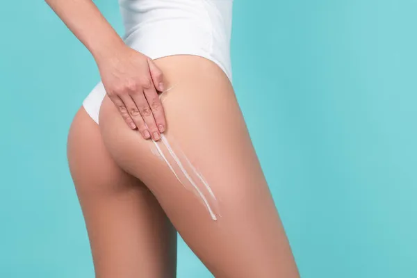 Cosmetic cream on woman buttocks with clean soft skin. Applying moisturizer cream on butt. Cellulite or anti cellulite treatment. Body care and spa salon concept. — Photo