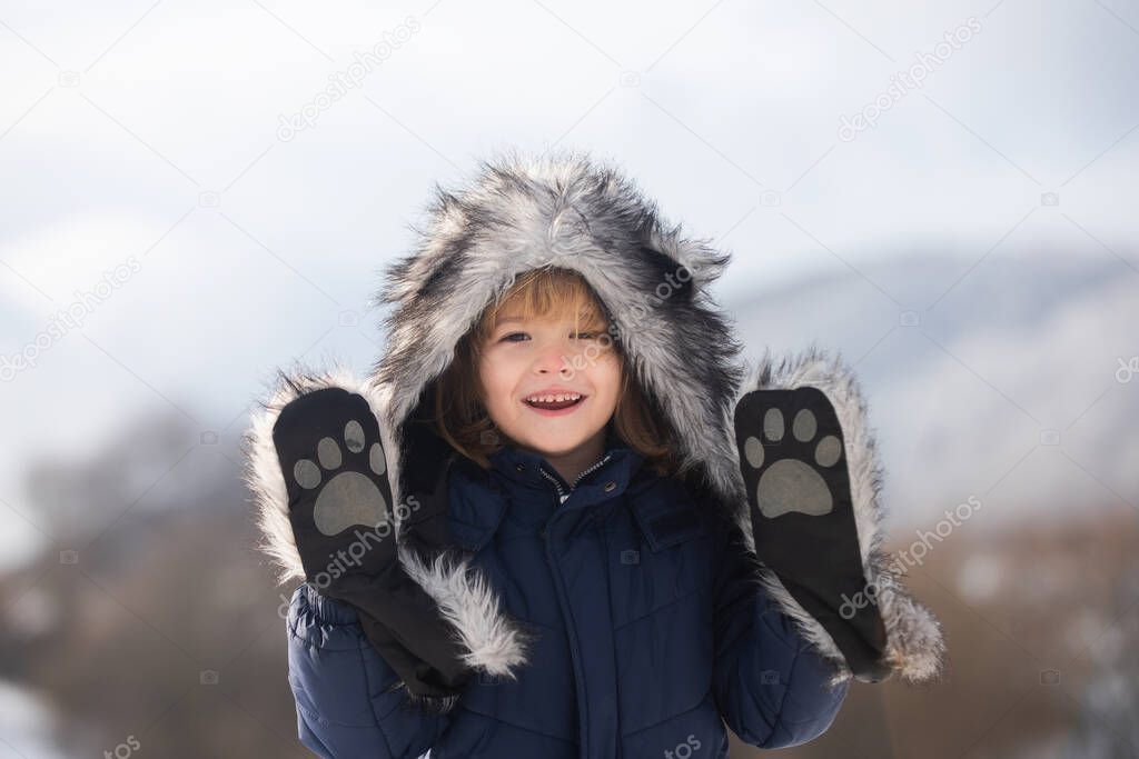 Funny little child boy in winter outdoor in frost snowy day outdoor.