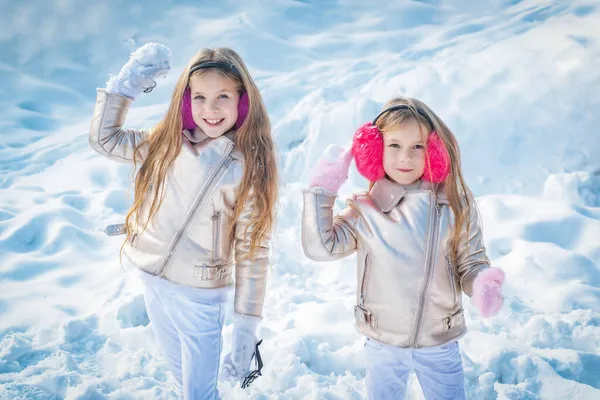 Roliga små flickor som leker med snö i parken. Porträtt av två små flickor leker med snö på vintern. Söta systrar leker i snö med snöbollskrig. — Stockfoto