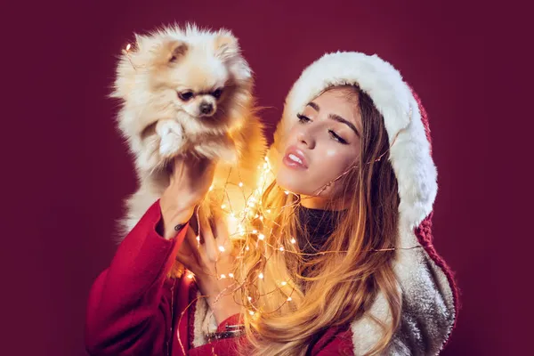 Γυναίκα με pomeranian spitch dog στα Χριστούγεννα. Κορίτσι με στολή Άγιου Βασίλη με κατοικίδιο. Χριστούγεννα και χειμερινές διακοπές. Νέο έτος του σκύλου — Φωτογραφία Αρχείου